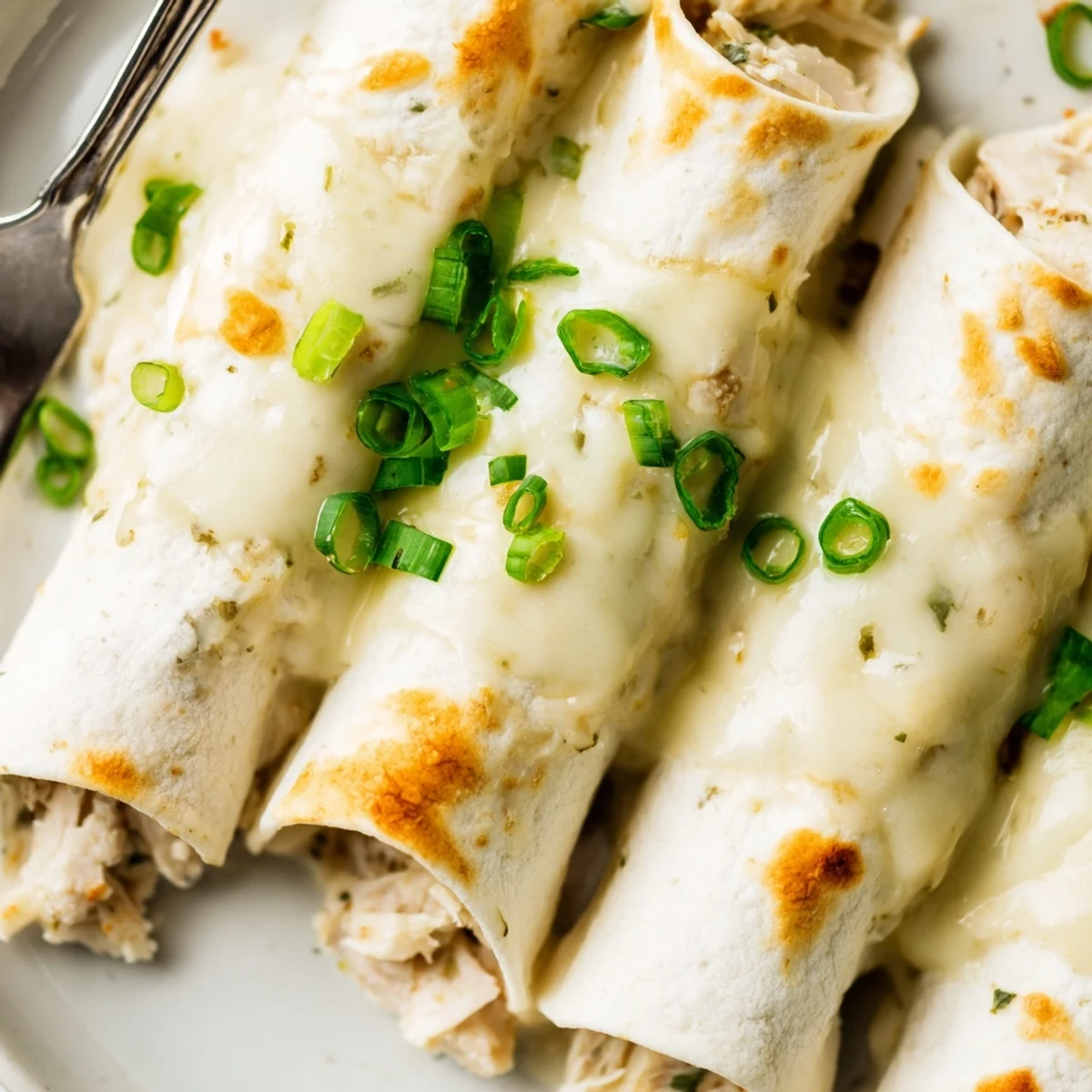 Baked until bubbly, silky white sauce blankets tender tortillas in Creamy White Chicken Enchiladas.