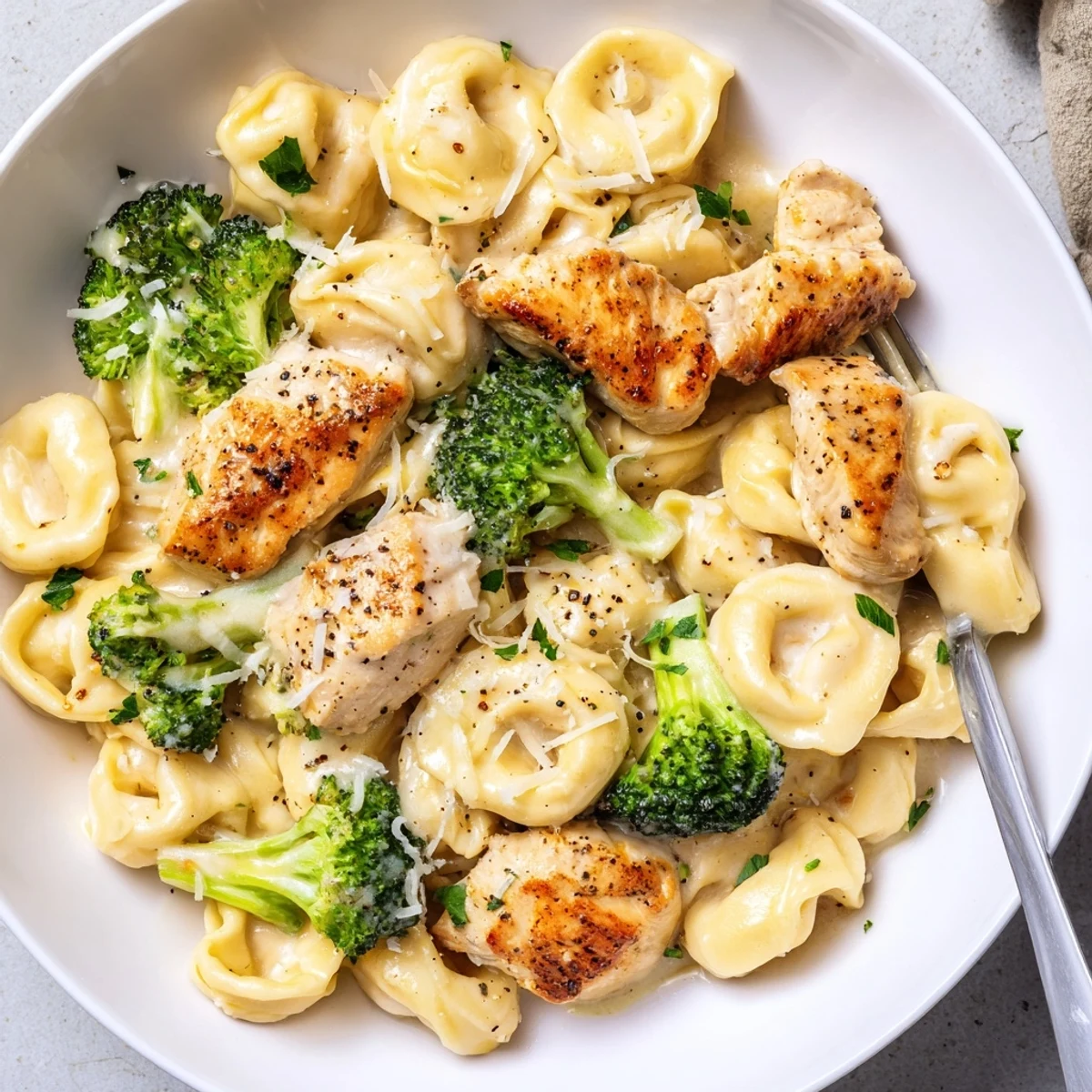 Plate of Creamy Garlic Parmesan Tortellini Chicken Broccoli Recipe, garnished with parsley  