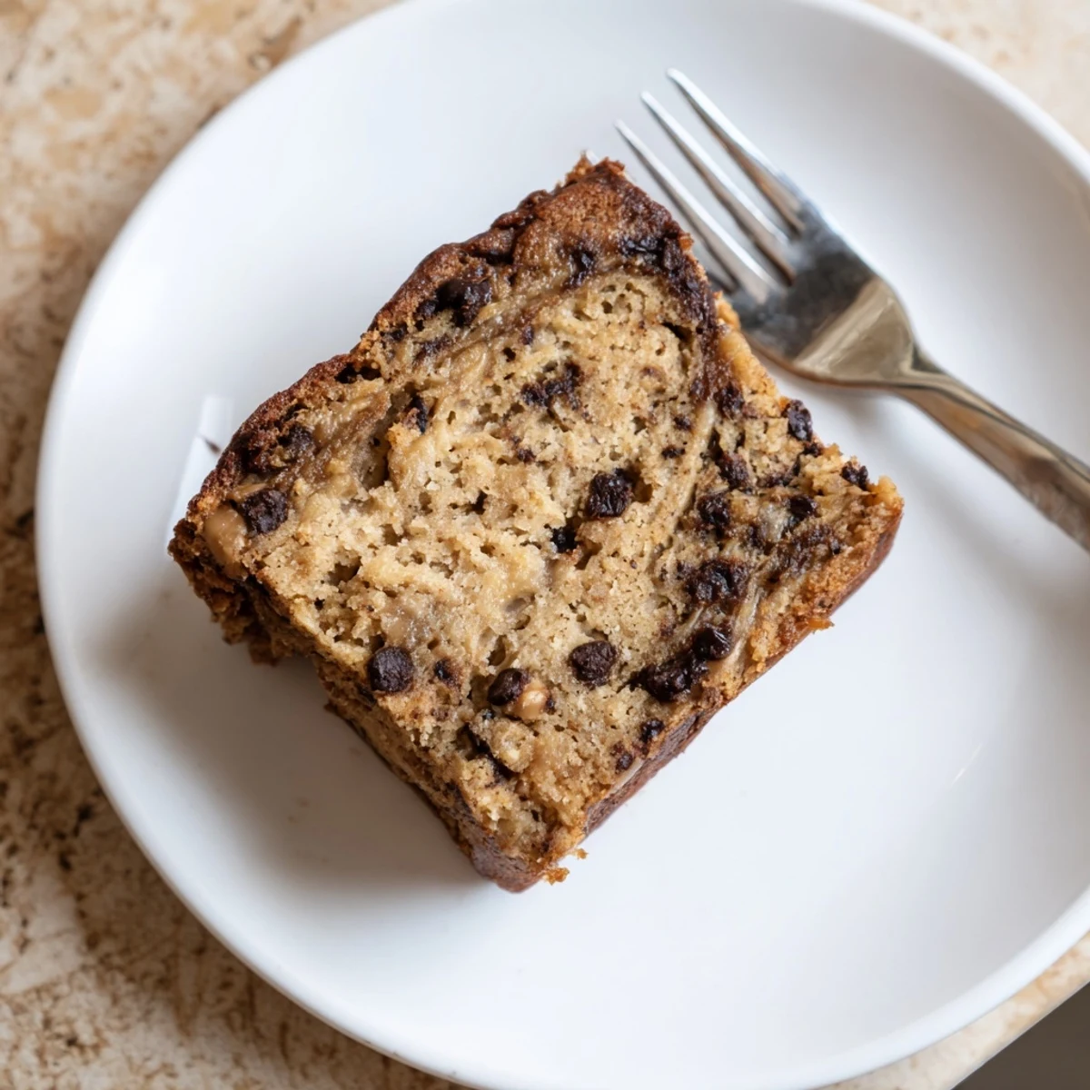 Thick slice of moist gluten-free peanut butter banana bars topped with flaky sea salt garnish