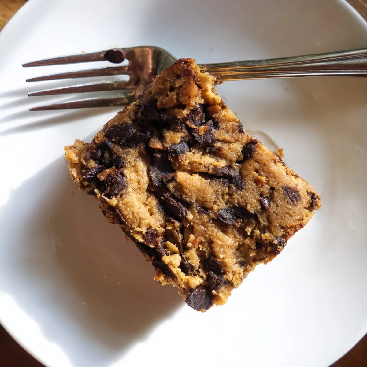 Freshly baked flourless peanut butter banana dessert squares cooling on parchment paper in baking pan