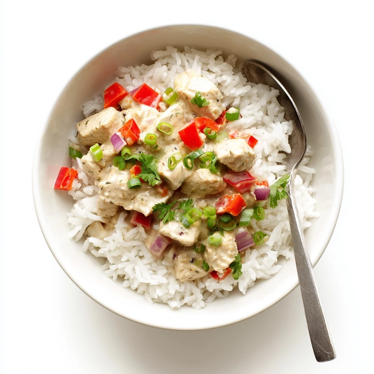 Spoonful of creamy Cajun chicken rice bowl showcasing spicy chicken pieces in velvety white sauce