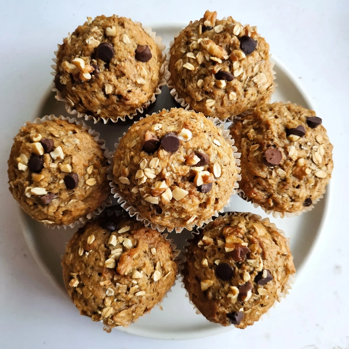 Golden brown banana oatmeal muffins topped with oats, fresh from the oven
