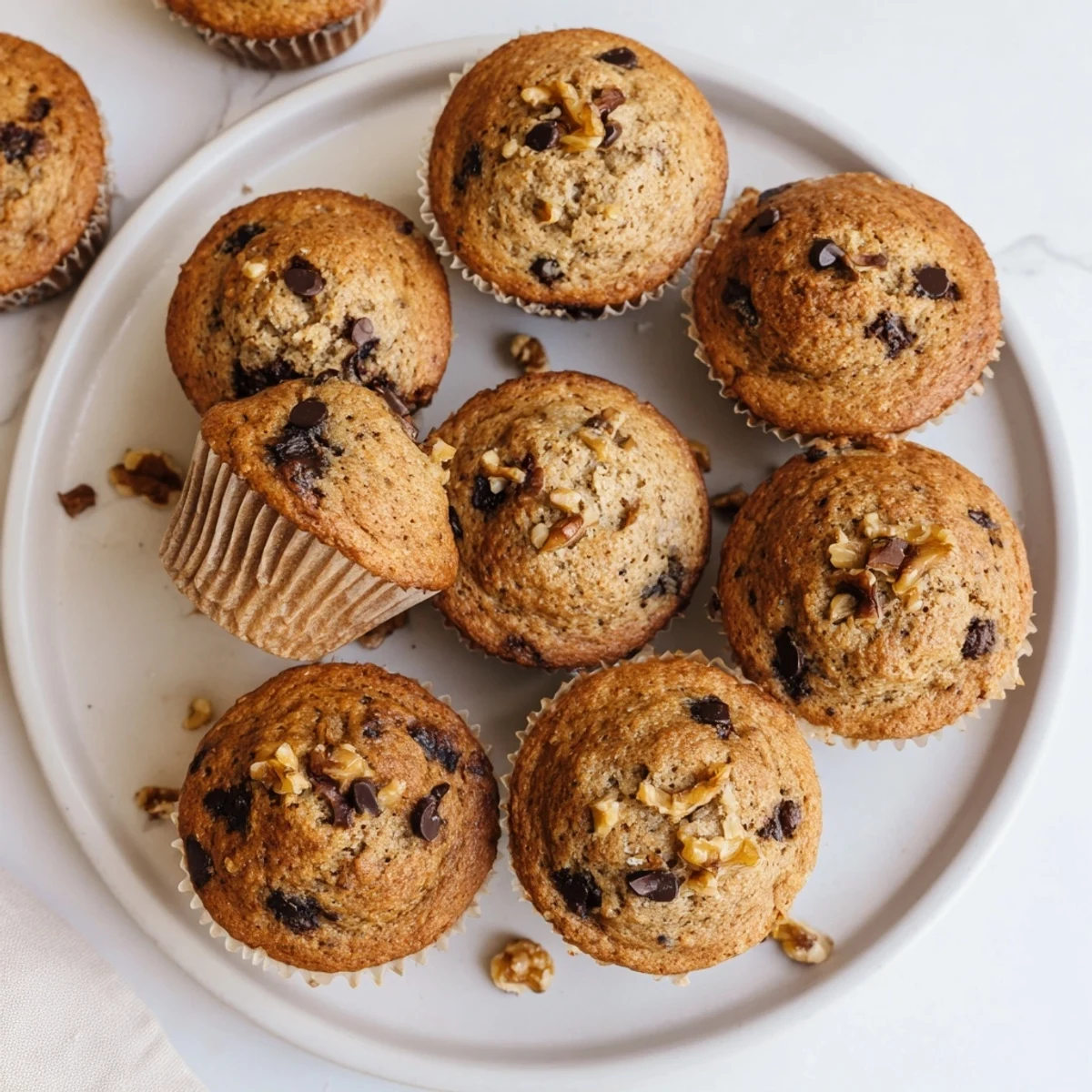 Moist whole wheat healthy banana nut muffins cooling on a wire rack with speckled banana texture and chopped nuts