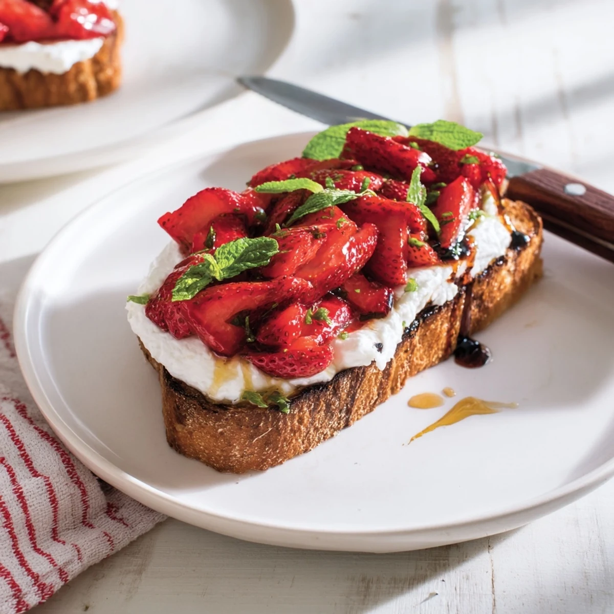 Roasted strawberry whipped ricotta toast garnished with fresh mint and extra honey drizzle