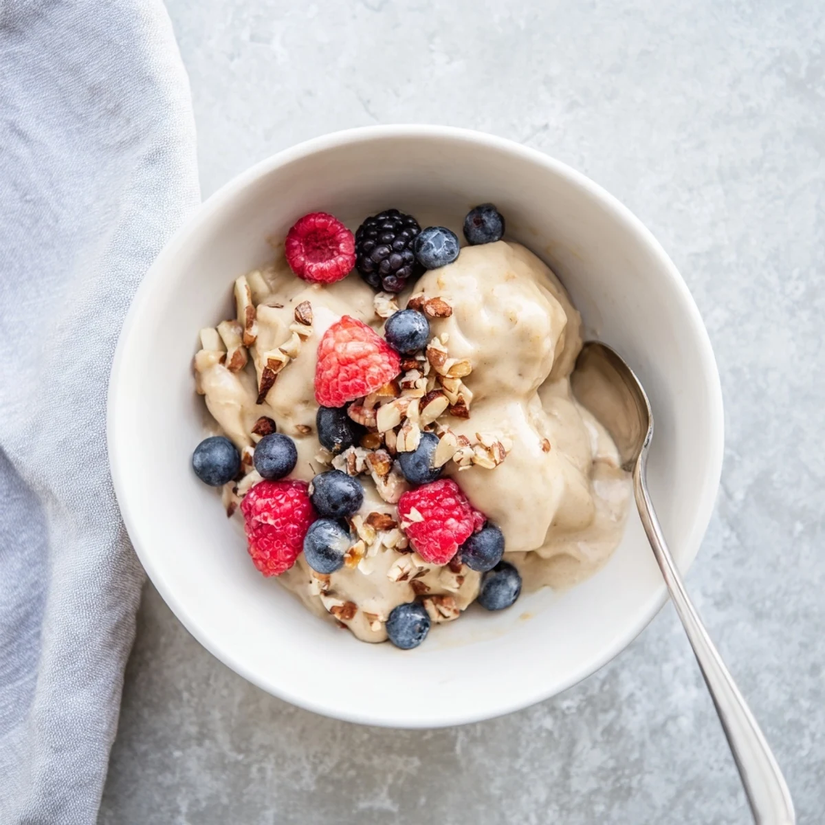 Creamy banana nice cream topped with fresh berries and chopped nuts in a bowl
