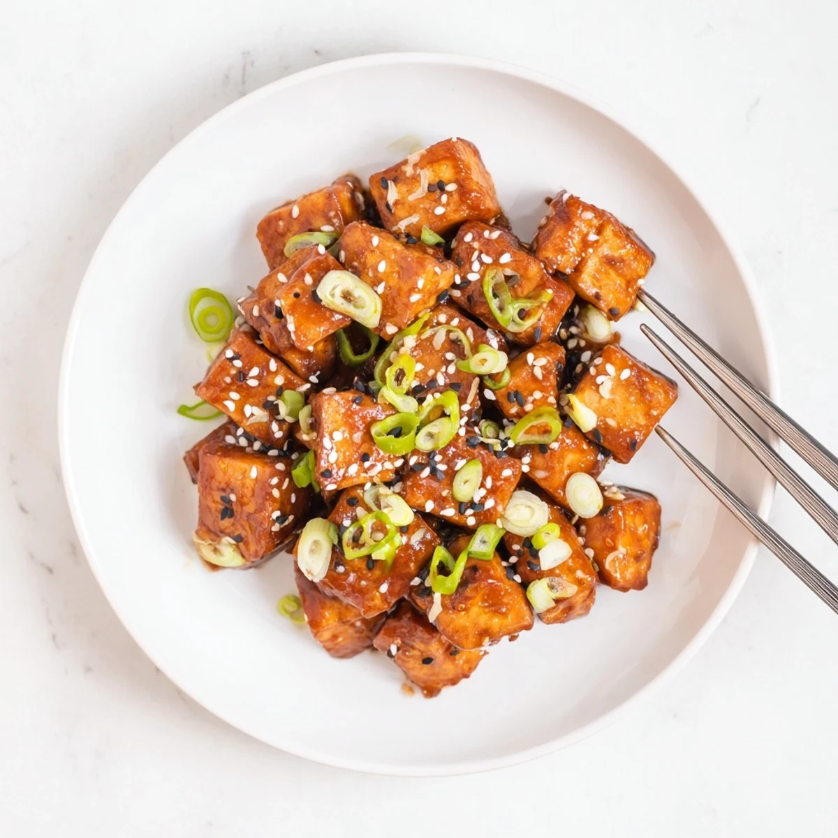 Pan-fried honey garlic tofu pieces coated in thick glossy honey garlic glaze