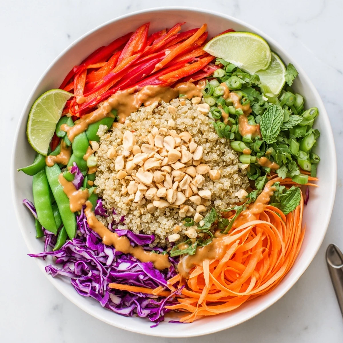 Bowl of Thai Quinoa Crunch Salad topped with chopped peanuts and lime