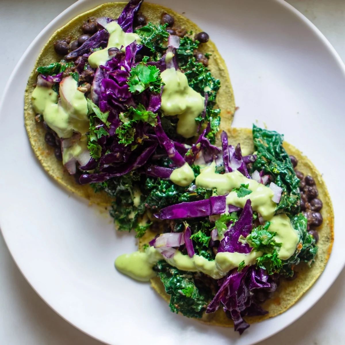 Crispy cabbage and herby avocado sauce top these smoky black bean kale tacos