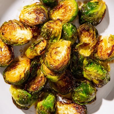 Roasted Brussels Sprouts with Balsamic Vinegar tossed with toasted walnuts and fresh parsley on a wooden board.