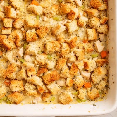A warm Dollys Chicken Stuffing Casserole sits beside a fresh green salad on a rustic table.