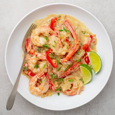 A close-up of Creamy Coconut Shrimp Buffet Style in a velvety sauce with lime wedges.