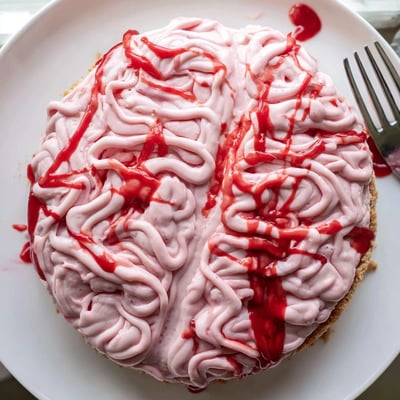 No Bake Strawberry Cheesecake Brain sliced to reveal creamy pink filling atop a buttery graham cracker crust
