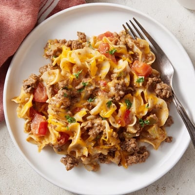 Golden-topped Beef Noodle Casserole steaming in dish, served with garlic bread.